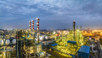 Fototapeta premium Illuminated oil refinery and chemical plant complex at night, showcasing extensive industrial infrastructure and energy production in a sprawling industrial area.