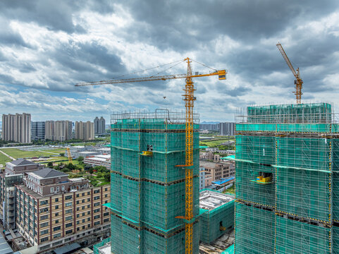 Active construction site with a crane and building in progress, set against a cloudy sky within the city. - Powered by Adobe