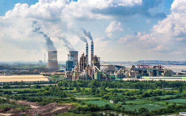 Industrial plant with smoking chimneys and nature landscape.