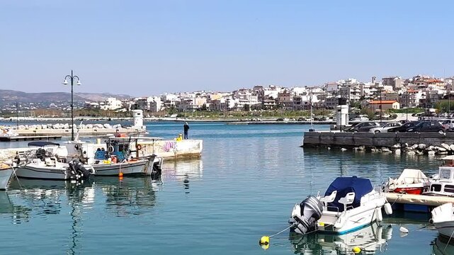 Video of traditional Greek fishing boats docked in the Corinth marina, Peloponnesus, Greece, with calm waters and a scenic coastal backdrop.