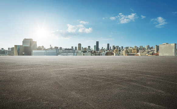 Panoramic empty wide asphalt road and modern city skyline under the sunlight.