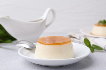 Tasty pudding with caramel sauce served on white table, closeup