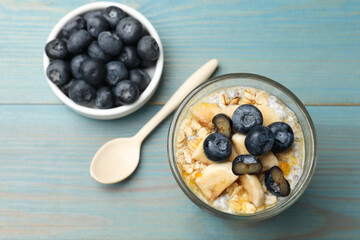 Delicious chia pudding with blueberries, banana and oatmeal in glass served on light blue wooden table, top view