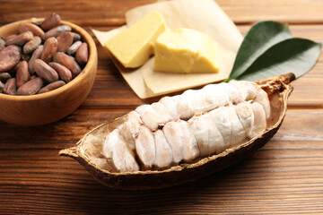 Cocoa pod with beans and butter on wooden table, closeup