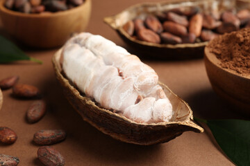 Cocoa pod with beans and powder on brown background, closeup