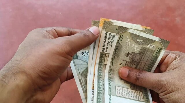 Blind person hand touch money surface for identifying or counting indian rupees currency notes. Extreme closeup top view. Raised dots and tactile cues on banknote concept.