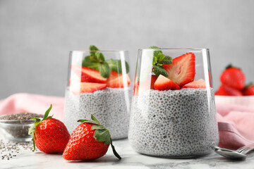 Delicious chia pudding with strawberries and mint on white marble table, closeup