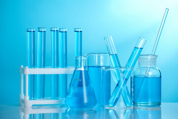 Laboratory glassware with liquid on mirror surface against blue background