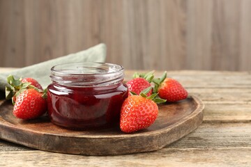 Delicious strawberry sauce and fresh berries on wooden table, closeup. Space for text