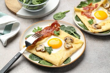 Delicious crepes with eggs, bacon and mushrooms served on grey table, closeup. Breton galette