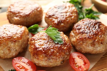 Delicious patties with parsley and tomato on table, closeup