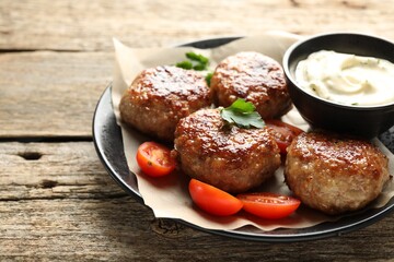 Delicious patties, parsley, tomatoes and sauce on wooden table, closeup. Space for text