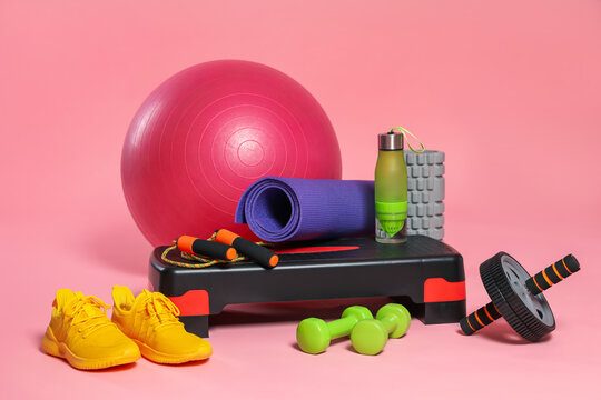 Many different fitness equipment on pink background