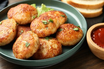 Delicious patties, parsley and ketchup on wooden table, closeup