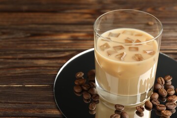 Coffee cream liqueur in glass and beans on wooden table, closeup. Space for text