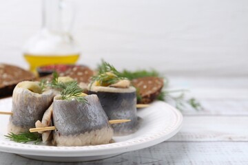 Delicious herring rolls with olives, dill and bread on white wooden table, closeup. Space for text