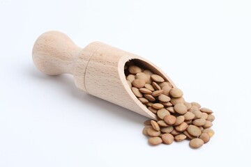 Raw lentils in wooden scoop isolated on white