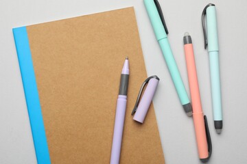 Copybook and pens on grey background, flat lay