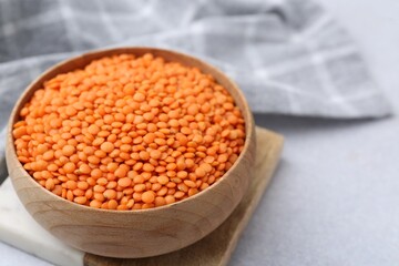 Red lentils in bowl on light table, closeup