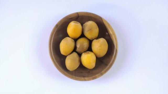 A group of fresh young dates or rutob dates or ruthob dates on a wooden plate with a white background.