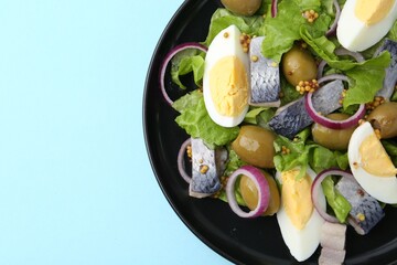 Delicious salad with herring, egg, mustard and vegetables on light blue background, top view. Space...