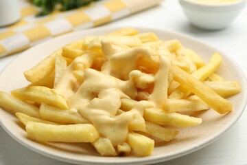 French fries with cheese sauce on white table, closeup