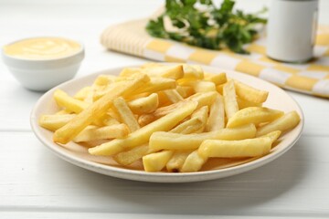 French fries with cheese sauce and parsley on white wooden table, closeup