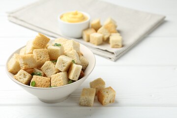 Delicious crispy croutons with parsley and sauce on white wooden table, closeup