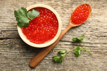 Red caviar and parsley on wooden table, flat lay