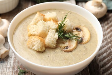 Delicious mushroom cream soup with croutons, dill and ingredients on wooden table, closeup