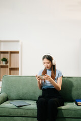 Asian woman using the smartphone and tablet on the sofa at home.