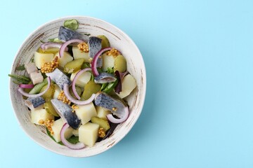 Delicious salad with herring, vegetables and mustard on light blue background, top view. Space for text