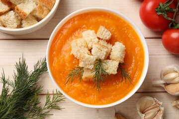 Delicious pumpkin cream soup with croutons, dill and ingredients on wooden table, flat lay