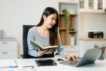 Asian woman sitting at a desk using a laptop computer Navigating Finance and Marketing