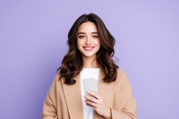 Naklejka premium Smiling woman with wavy hair holds a smartphone device