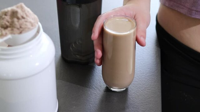 Close up of woman pouring a protein shake into a glass. Diet meal replacement for weight loss