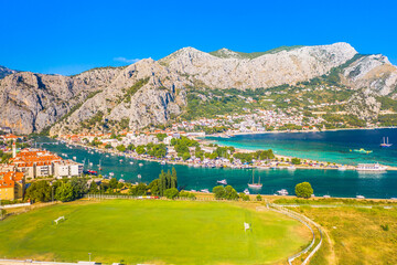 Aerial view of the historic town of Omiš, Croatia, nestled between the towering Biokovo Mountain and the Adriatic Sea, showcasing its stunning river canyon, and dramatic landscape