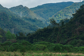 Fototapeta premium Xindian Wantan displays a majestic mountain landscape. Multiple layers of forested mountains create a stunning depth of field with various vegetation covering every slope.