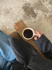 Woman sitting on chair holding coffee.