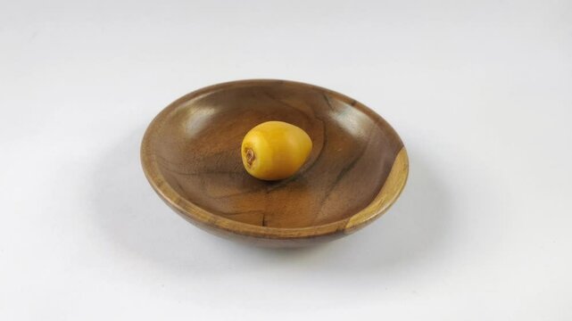 A fresh young dates or rutob dates or ruthob dates on a wooden plate with a white background.