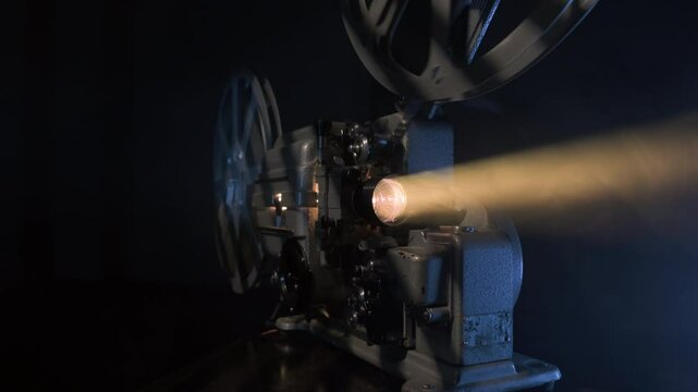 Old 16mm film projector with diffuse light beam, movie screening.