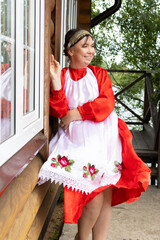 Obraz premium a woman in a national Udmurt costume. small nations.A woman in a national costume stands at the cottage, summer