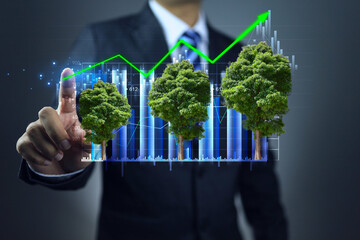 Businessman point hand to tree graph with head up direction to represent investment in green business ESG or clean energy, environmentally friendly process that reduces carbon dioxide emissions.