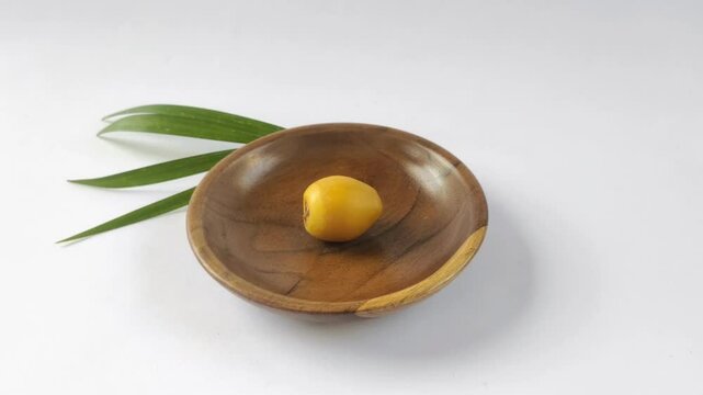 A fresh young dates or rutob dates or ruthob dates on a wooden plate with a white background.