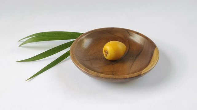 A fresh young dates or rutob dates or ruthob dates on a wooden plate with a white background.
