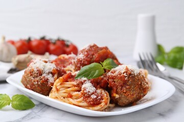 Delicious pasta with meatballs, basil and cheese on white marble table, closeup