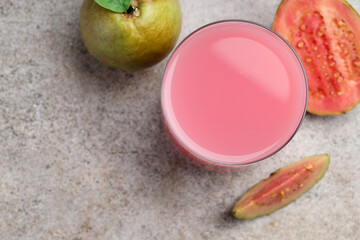Refreshing guava juice and fresh fruits on grey table, flat lay. Space for text