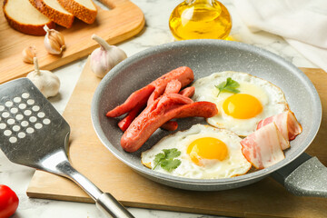 Tasty brunch. Fried eggs, sausages, bacon and spatula on white marble table, closeup