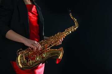 Naklejka premium Professional musician with saxophone on black background, closeup