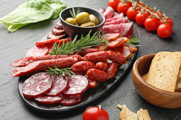 Different smoked sausages and other snacks on black table, closeup